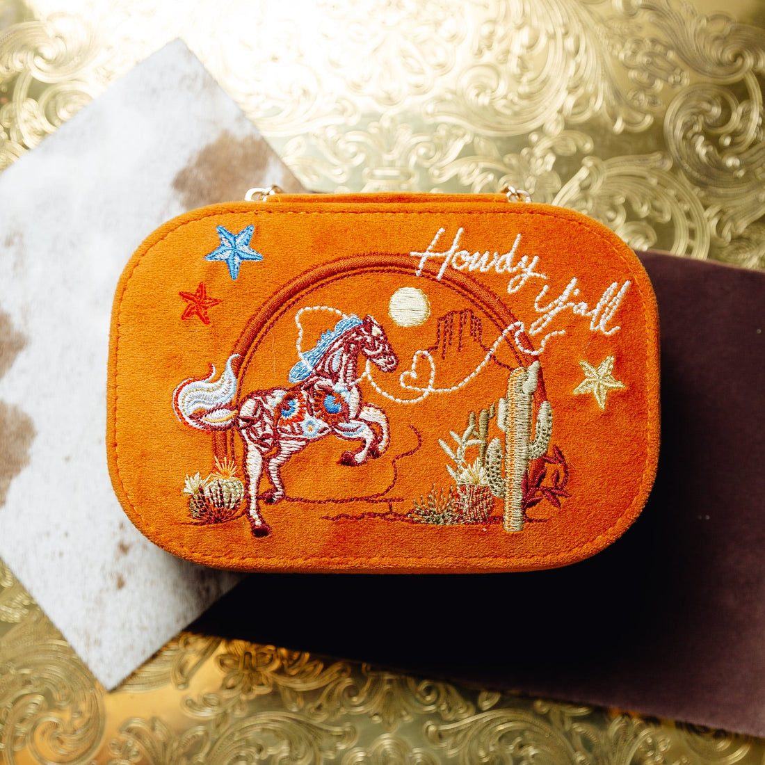 Embroidered Texas velvet orange travel jewelry box with horse design on a beige background. Spirit of Texas Burnt Orange Velvet Embroidered Travel Jewelry Box. Jewelry Dallas.