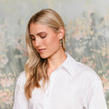 Woman wearing a white shirt against a blurred floral background