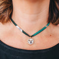 A close-up of a person's neck and chest wearing a delicate gold chain necklace with a custom circular pendant featuring a dog portrait surrounded by small clear stones.