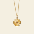 Gold necklace with a circular pendant on a beige background