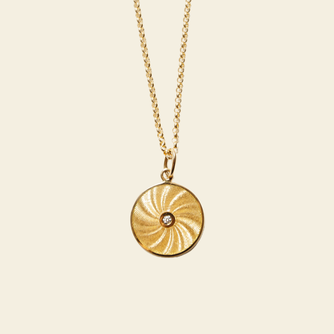 Gold necklace with a circular pendant on a beige background