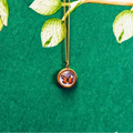 Butterfly-themed necklace on a green background with leaves
