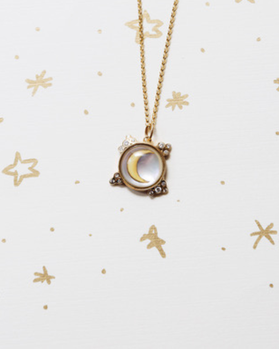 Necklace with a moon-phase pendant on a white background with gold stars
