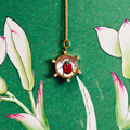 Necklace with a pendant featuring a ladybug design on a green background with floral elements.