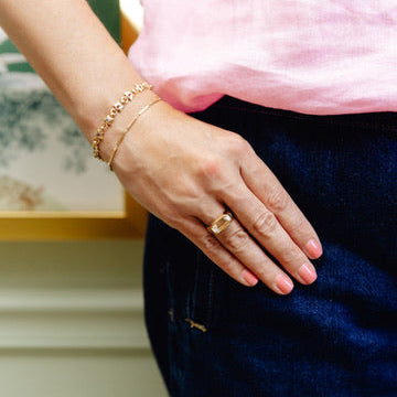 Close-up of a person's hand wearing a moonstone ring with a blurred background
