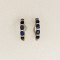 Pair of white gold hoop earrings with sapphires and pave diamonds on a white background