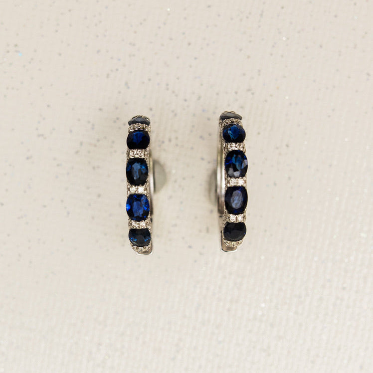 Pair of white gold hoop earrings with sapphires and pave diamonds on a white background