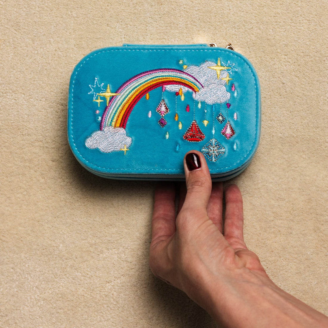 Blue velvet travel jewelry box with rainbow and cloud design on a beige background.  Jewels with Jules Velvet Embroidered Travel Jewelry Box. Jewelry Dallas.