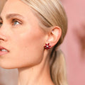 Close-up of a woman wearing red floral earrings with a blurred background