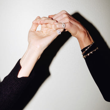 Two pairs of hands holding each other against a plain background