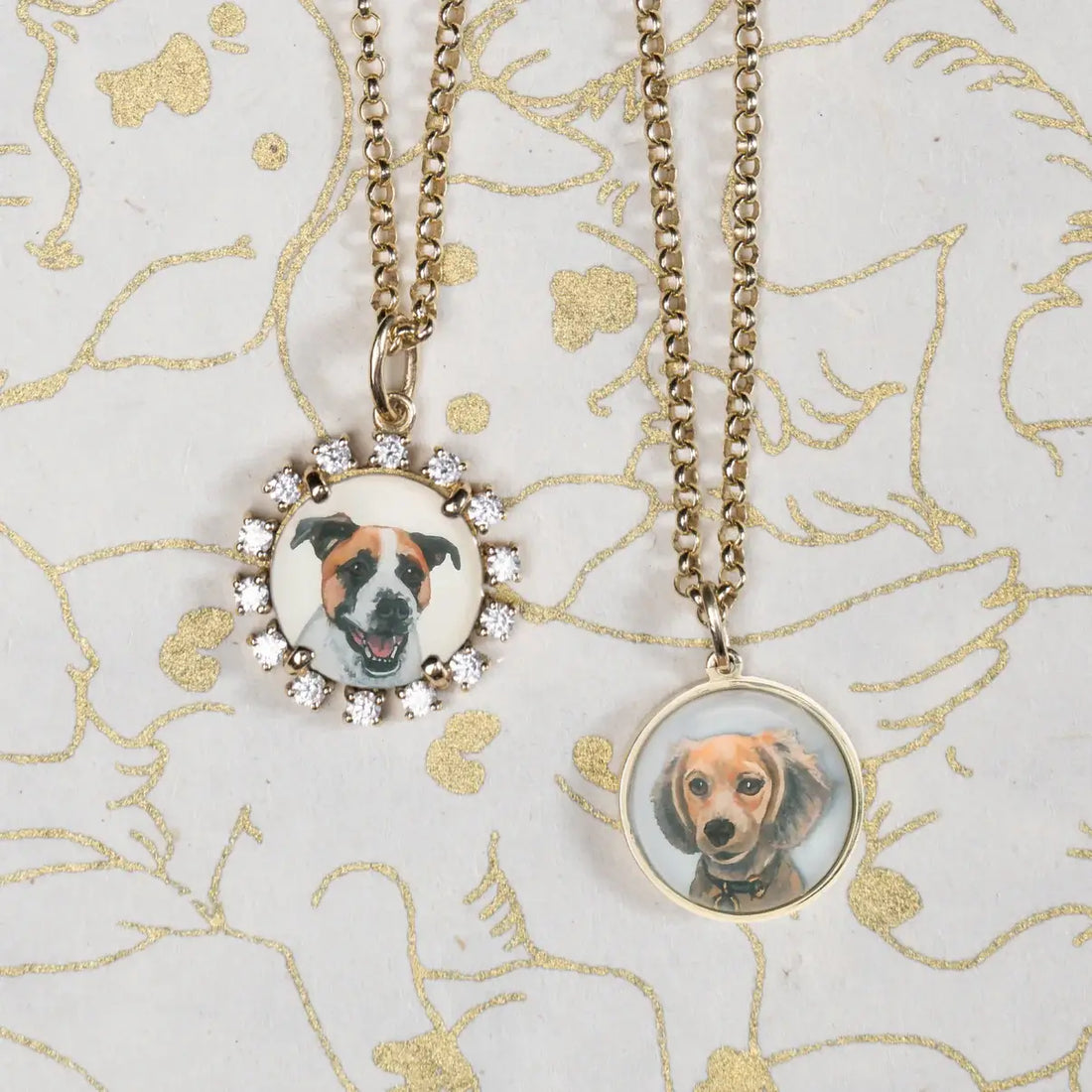 Two necklaces with circular pendants featuring dog portraits on a decorative background. Custom Pet Portrait. Hand-carved in Germany and painted in reverse intaglio on rock crystal, each charm is backed with luminous mother-of-pearl and set in your choice of 18K yellow, rose, or white gold. Jewelry Dallas.