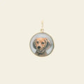 Gold pendant with a small circular photo of a dog on a beige background. Custom Pet Portrait. Hand-carved in Germany and painted in reverse intaglio on rock crystal, each charm is backed with luminous mother-of-pearl and set in your choice of 18K yellow, rose, or white gold. Jewelry Dallas.