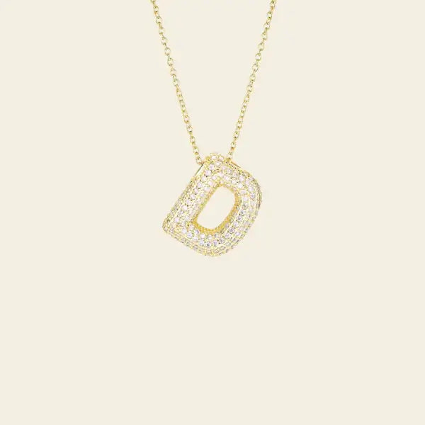 Gold necklace with a diamond-studded pendant on a beige background. Diamond Letter Pendant. Length and Layering: 16" Necklace with 2"Extension
Available in 14K Yellow Gold
Details: Initial with 1.00 carat of pavé diamonds in 14K Yellow Gold. Jewelry Dallas.