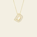 Gold necklace with a diamond-studded pendant on a beige background. Diamond Letter Pendant. Length and Layering: 16