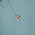 Necklace with a 'D' pendant on a teal background. Diamond Letter Pendant. Length and Layering: 16