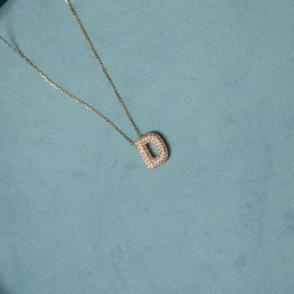 Necklace with a 'D' pendant on a teal background. Diamond Letter Pendant. Length and Layering: 16" Necklace with 2"Extension
Available in 14K Yellow Gold
Details: Initial with 1.00 carat of pavé diamonds in 14K Yellow Gold. Jewelry Dallas.