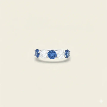 Ring with sapphires and diamonds on a beige background. Five Stone Blue Sapphire and Diamond Ring. # of Diamonds:2 Carat Weight:0.60 carat Shape:RoundColor:G-HClarity:SI1-SI2Cut:Excellent # of Sapphires:3Carat Weight:2.10 carats Shape:RoundColor:BlueClarity:Eye CleanCut:Excellent. 14k gold. Jewelry Dallas.