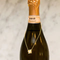 Bottle of Rosé wine with a gold necklace draped over it against a neutral background. Flower Power. Length: 16