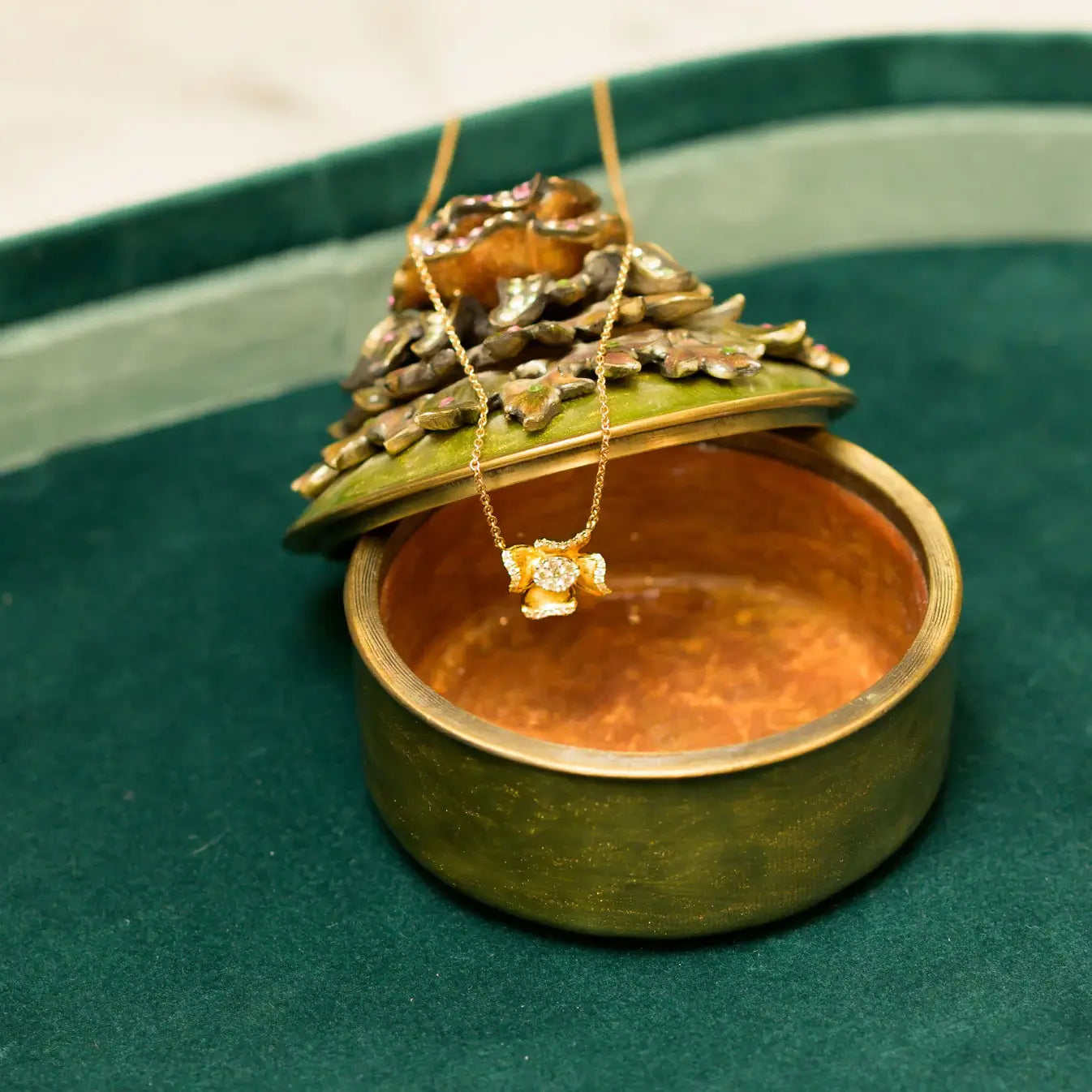 Green jewelry box with a gold necklace on a green background. Flower Power. Length: 16"+2" Link Chain Materials: Solid 14kt Gold with Natural Diamonds. Jewelry Dallas.