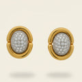 Gold earrings with diamond-pave centers on a beige background. Gold & Diamond Pavé Oval Earrings. These oval earrings are crafted in rich 14k yellow gold and set with 1 carat of natural pavé diamonds for radiant sparkle. Jewelry Dallas.