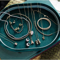 Jewelry set including necklaces, bracelets, and earrings on a green velvet tray. Green Velvet Jewelry Tray. Jewelry Dallas.