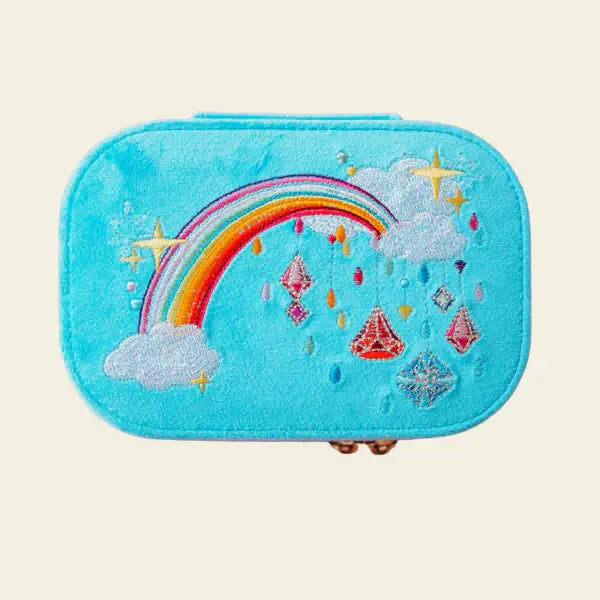 Blue velvet travel jewelry box with rainbow and cloud design on a beige background.  Jewels with Jules Velvet Embroidered Travel Jewelry Box. Jewelry Dallas.