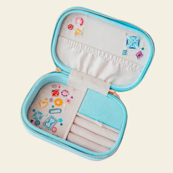 Blue velvet travel jewelry box with rainbow and jewel design on a beige background. Jewels with Jules Velvet Embroidered Travel Jewelry Box. Jewelry Dallas.