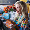 Woman holding a colorful travel jewelry boxes in a vibrant setting. Jewels with Jules Velvet Embroidered Travel Jewelry Box. Jewelry Dallas.