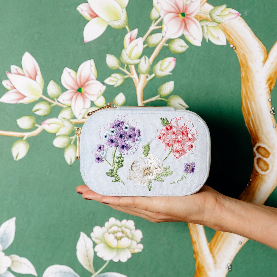 Light blue velvet travel jewelry box with floral embroidery on a beige background. Blooming with Cheer Light Blue Velvet Embroidered Travel Jewelry Box. Jewelry Dallas.