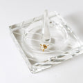 Gold five-point star stud earring with a pale faceted center displayed on clear glass.