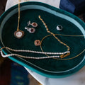 Jewelry, including necklaces and earrings on a green velvet jewelry tray. One-of-a-Kind Pendant with Pink Tourmaline. The pendant is set in solid 14K gold with a blend of polished and subtly textured details that add richness and character. It hangs from a 3.2mm rolo chain. Jewelry Dallas.
