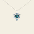 Necklace with a blue gemstone pendant on a beige background. One-of-a-Kind Pendant with Teal Blue Sapphire. Captivating teal blue sapphire set in 14K white gold. The pendant hangs from a delicate yet durable 1.3mm 14K white gold cable chain. Jewelry Dallas.