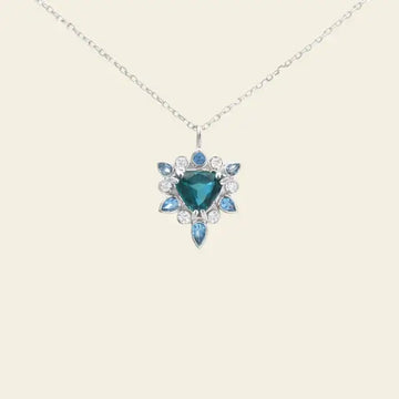 Necklace with a blue gemstone pendant on a beige background. One-of-a-Kind Pendant with Teal Blue Sapphire. Captivating teal blue sapphire set in 14K white gold. The pendant hangs from a delicate yet durable 1.3mm 14K white gold cable chain. Jewelry Dallas.