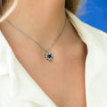 Necklace with a pendant worn by a person against a blue background. One-of-a-Kind Pendant with Teal Blue Sapphire. Captivating teal blue sapphire set in 14K white gold. The pendant hangs from a delicate yet durable 1.3mm 14K white gold cable chain. Jewelry Dallas.