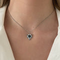 Necklace featuring a blue sapphire gemstone on a person wearing a white shirt. One-of-a-Kind Pendant with Teal Blue Sapphire. Captivating teal blue sapphire set in 14K white gold. The pendant hangs from a delicate yet durable 1.3mm 14K white gold cable chain. Jewelry Dallas.