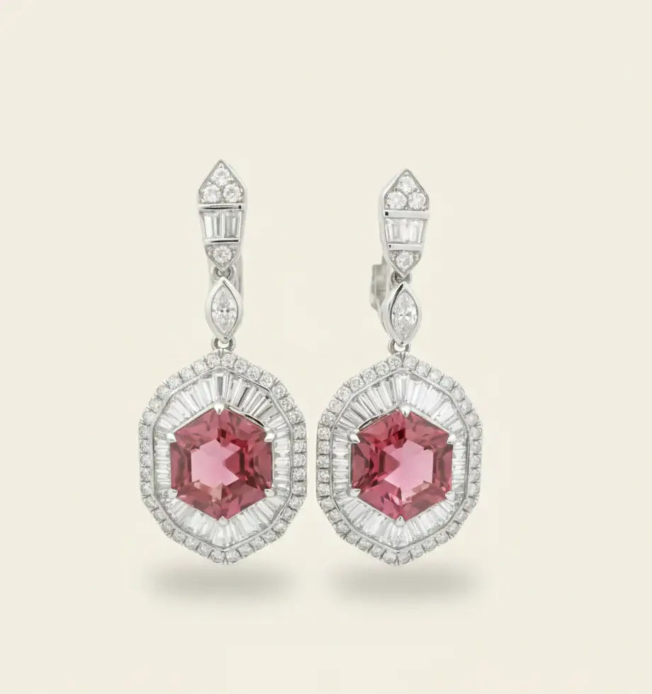 Pair of earrings with pink tourmaline and diamond accents on a light background. Pink Tourmaline Hexagon Drop Earrings with Diamonds. 9.10 carats of vibrant hexagon-cut pink tourmalines, accented by 2.84 carats of brilliant diamonds, set in 18k white gold. Jewelry Dallas.