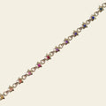 Gold bracelet with star-shaped charms and rainbow gemstones on a beige background. Rainbow Star Bracelet. Crafted in solid 14K yellow gold, each petite star is set with vibrant 0.80 carats of colored sapphires. Jewelry Dallas.