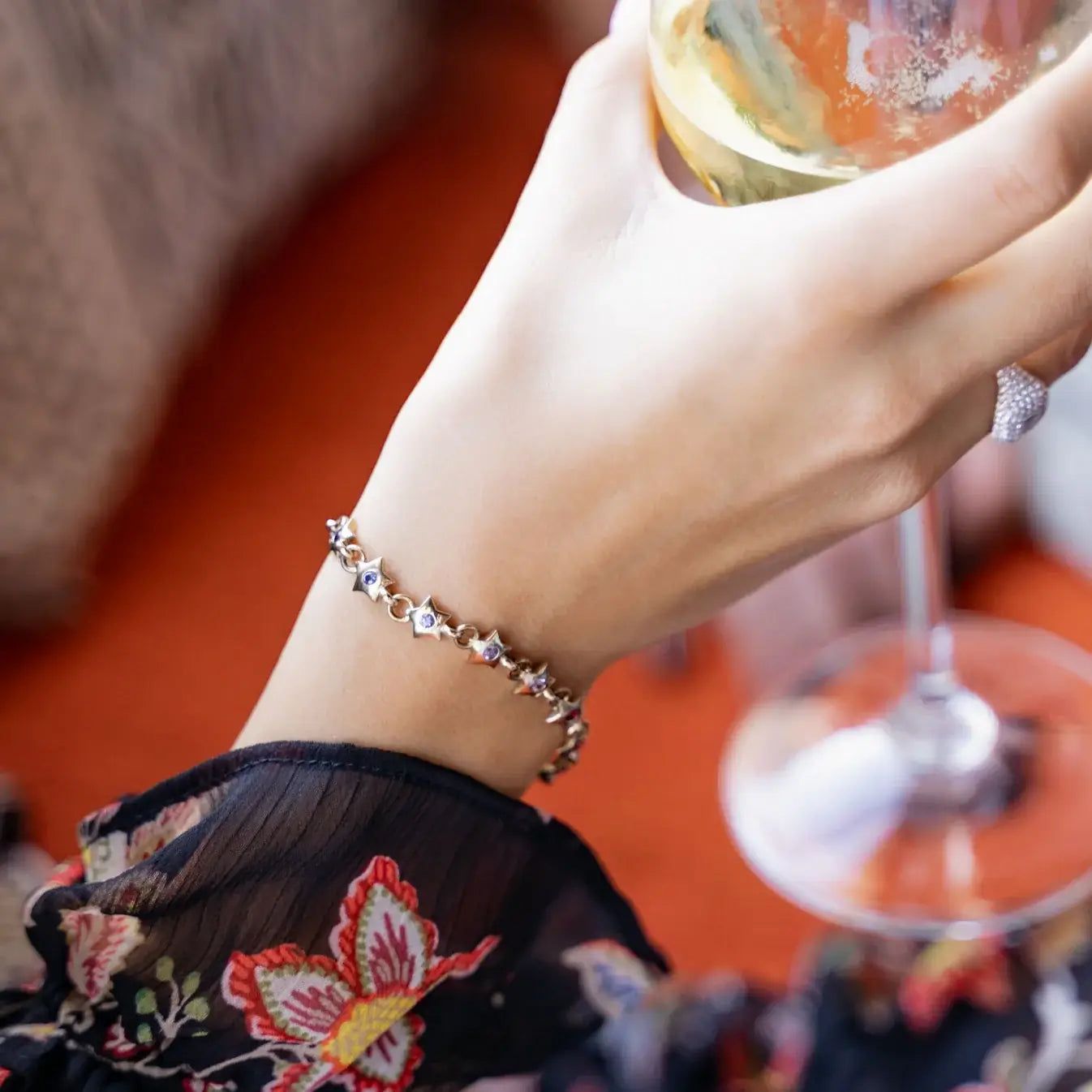 Gold bracelet with star-shaped charms and rainbow gemstones on a wrist. Rainbow Star Bracelet. Crafted in solid 14K yellow gold, each petite star is set with vibrant 0.80 carats of colored sapphires. Jewelry Dallas.