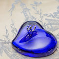 Blue heart-shaped object with a pair of hoop earrings with blue sapphires and diamonds. Sapphire and Pave Diamond Hoops. Material: Solid 18kt White Gold with 0.47 carats of Natural Diamonds and Sapphires totaling 2.23 carats. Jewelry Dallas.