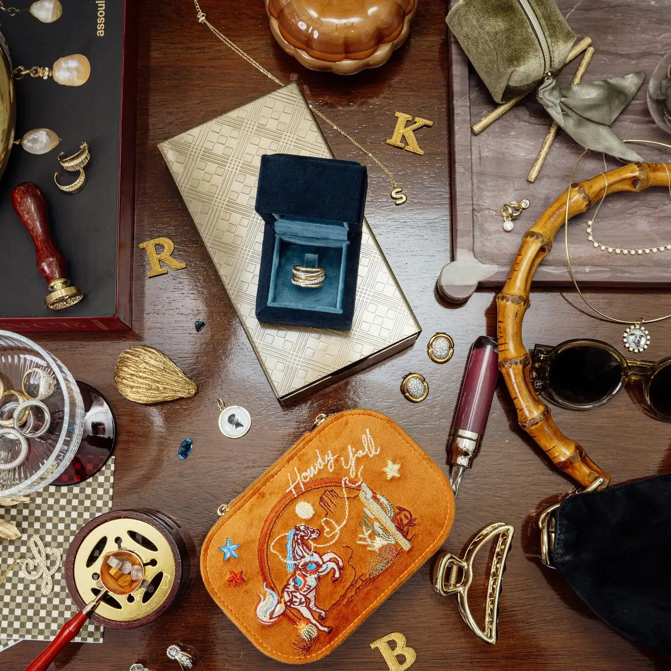 Collection of jewelry and accessories on a wooden surface. Spirit of Texas Burnt Orange Velvet Embroidered Travel Jewelry Box. Jewelry Dallas.