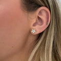 Close-up of an ear wearing a star-shaped earring with a diamond center. Star Studs. Materials: 18K Yellow Gold and Hand-Cut Natural Diamonds totaling 0.74 carats. Jewelry Dallas.