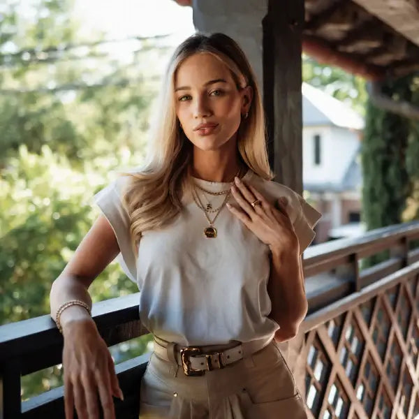 A woman standing on a wooden deck with greenery in the background, wearing a solid gold wax seal pendant necklace. Wax Seal Pendant Length: 16"+2" Link Chain
Material: 14kt Gold Over Sterling Silver .925 or solid 14kt Gold. Jewelry Dallas.