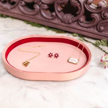 Pink jewelry tray with earrings on a white surface with decorative elements.